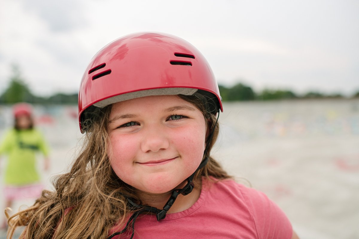 A cute happy girl smiling wearing pink red top helmet