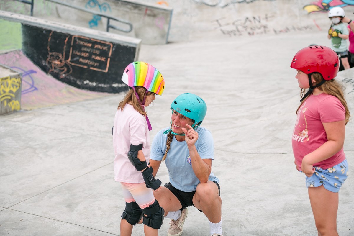 Two girls learning skateboard from the instructor.