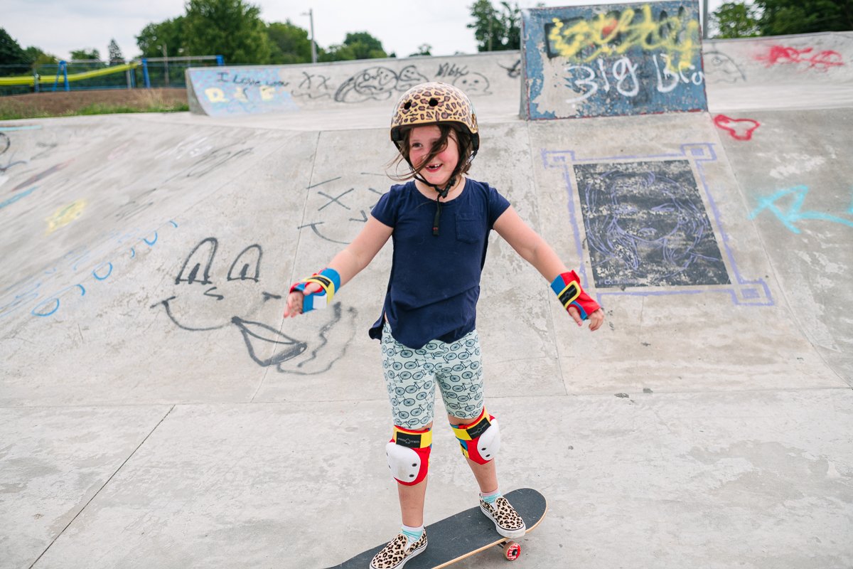 Small girl child wearing helmet and doing skateboards