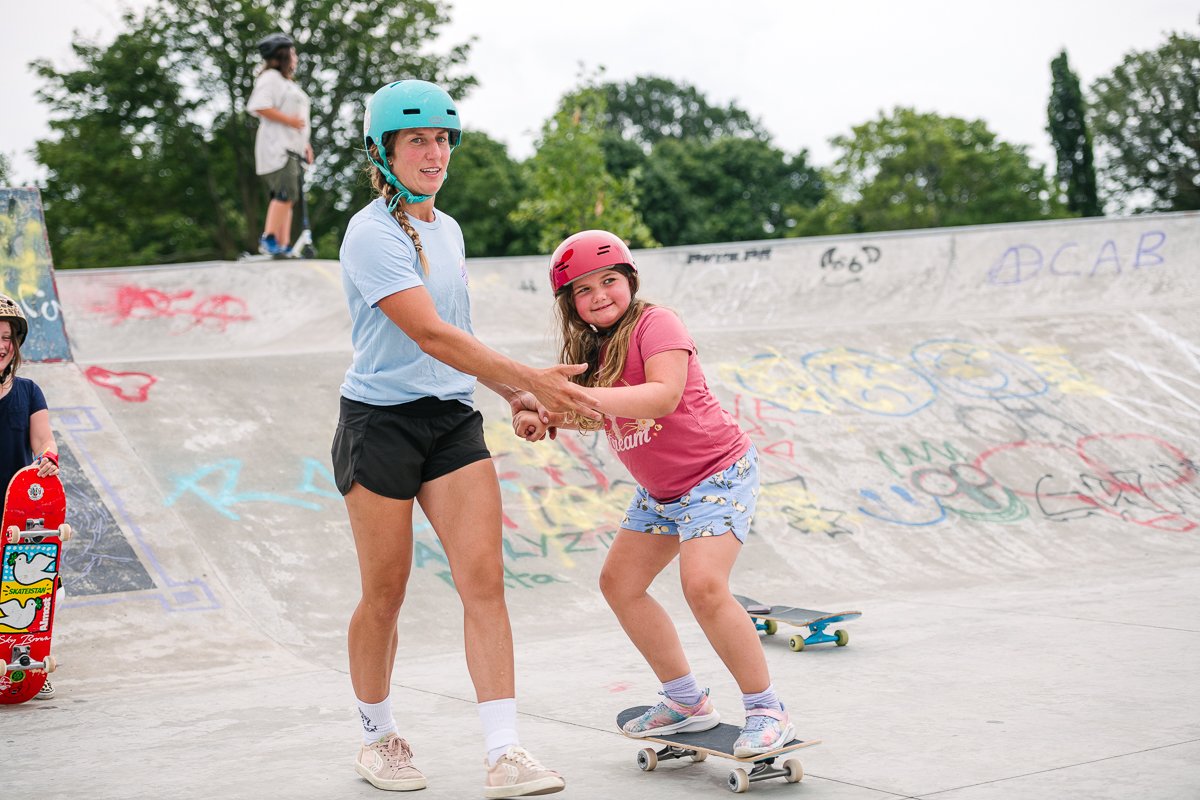 Instructor teaching skating to a small girl.
