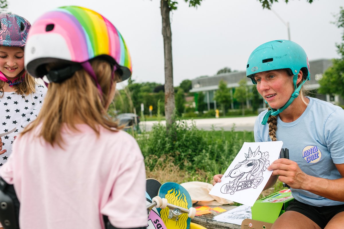 Small girl wearing rainbow helmet learning skateboard