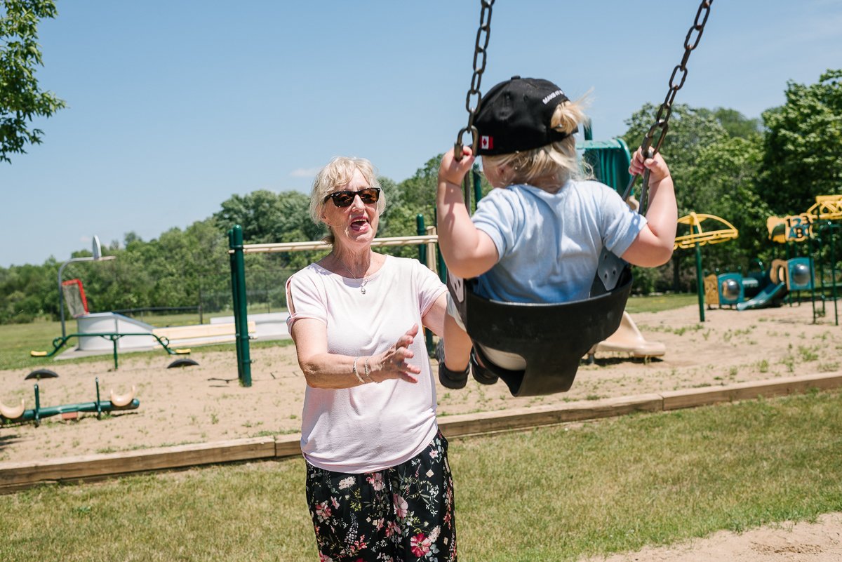 Grand mother holding baby while he is swinging in the park