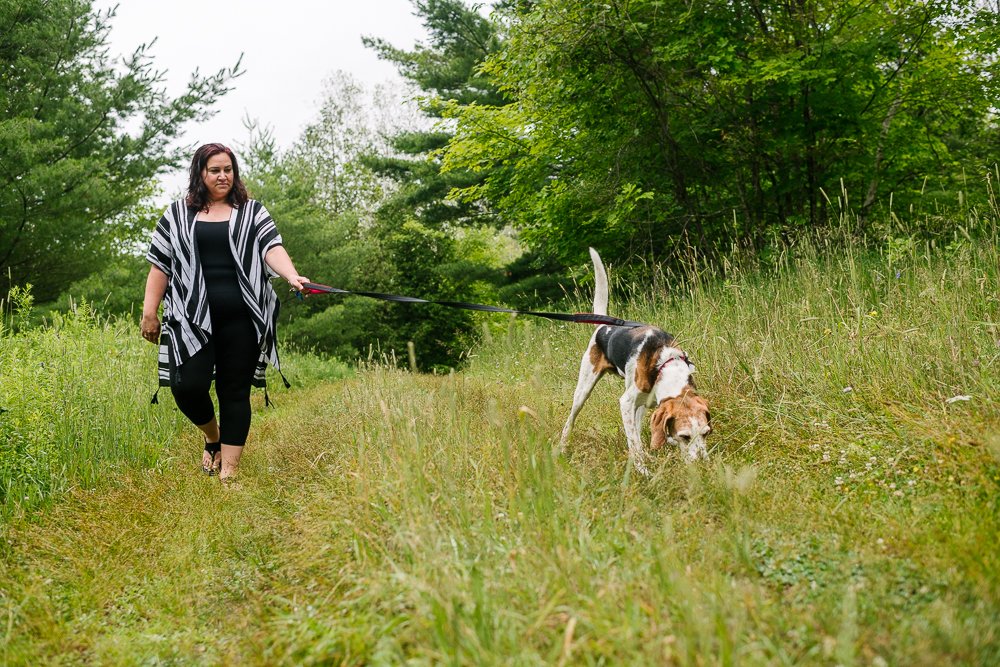 Women walking in the grass with her fur baby.