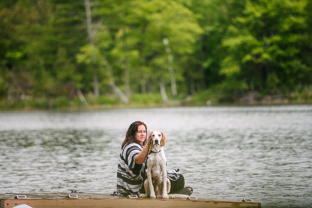 Woman loving her pet dog while they both are enjoying at the river side.
