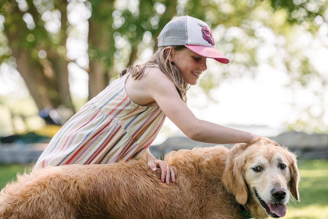 Girl wearing cap giving pat to her dog