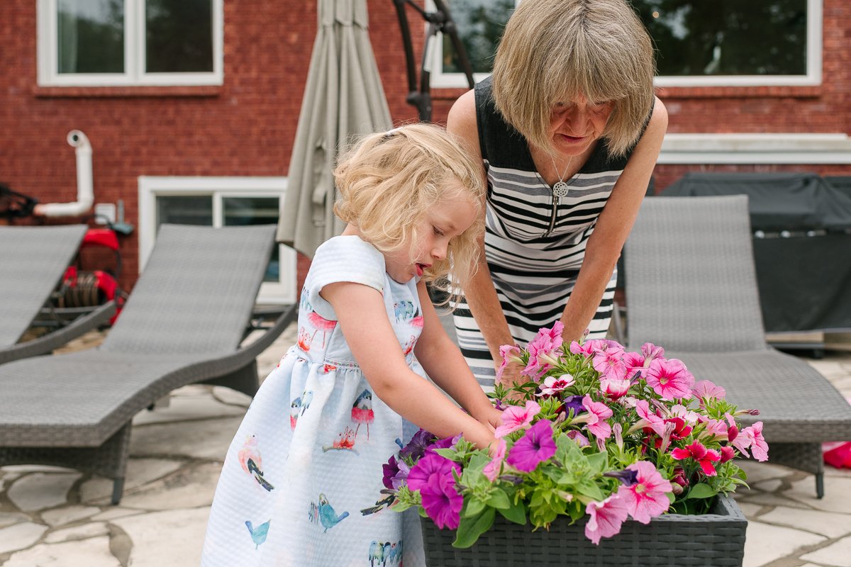 Woman and her little grandchild playing with pink and purple flowers