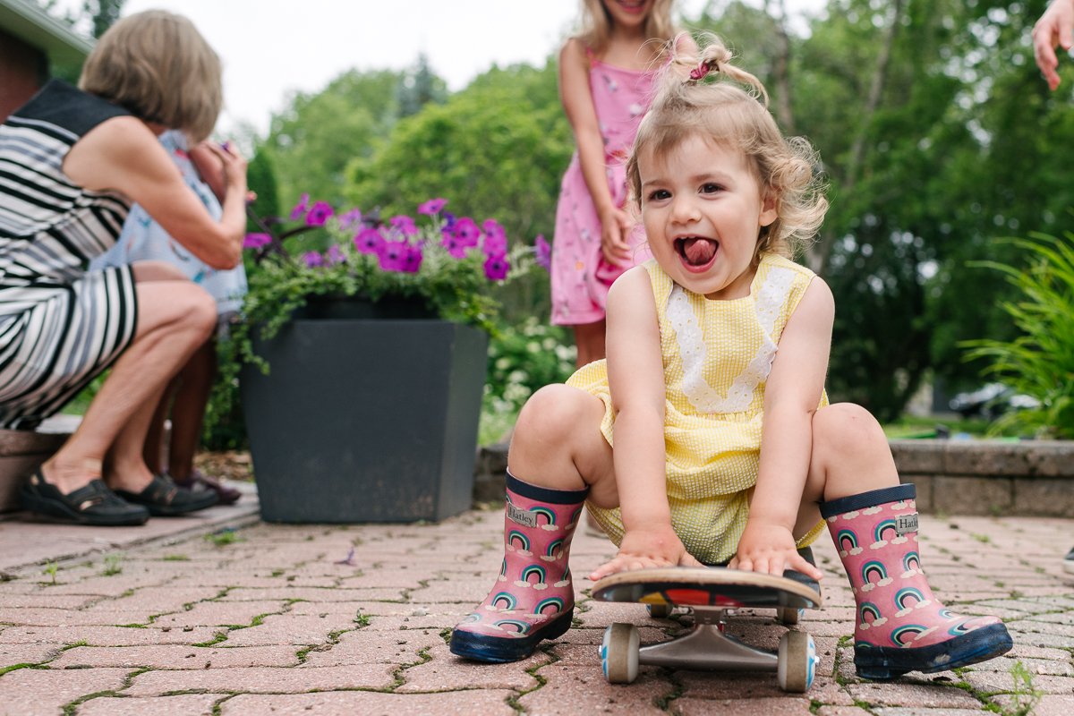 Little girl wearing yellow dress sitting on the skateboard.