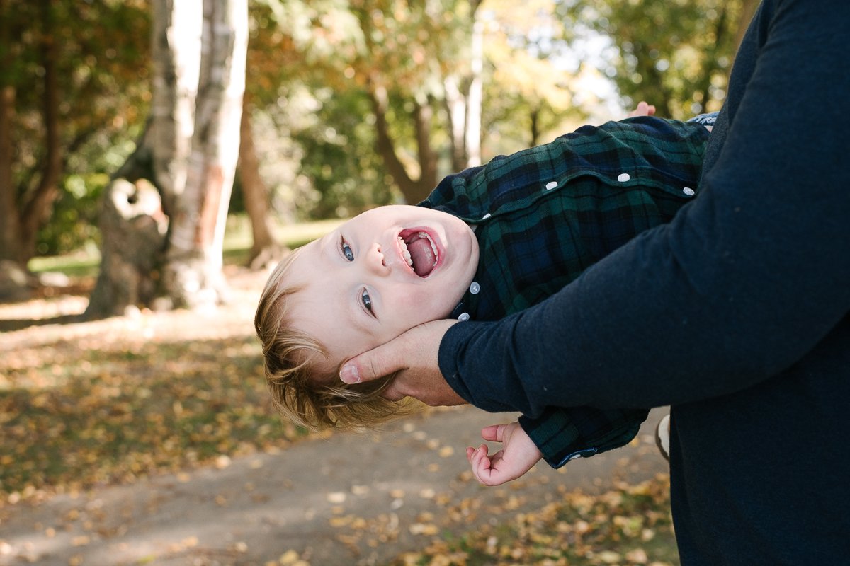 Little boy playing in his dads arms.