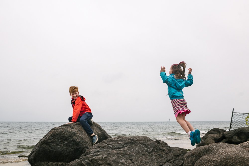 Kids playing near the lake jumping on the rocks