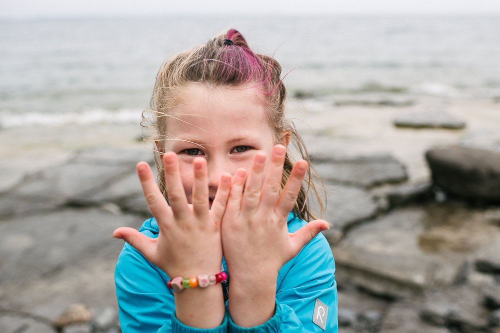 Girl showing her hand with pretty cute smile on her face near the lake.