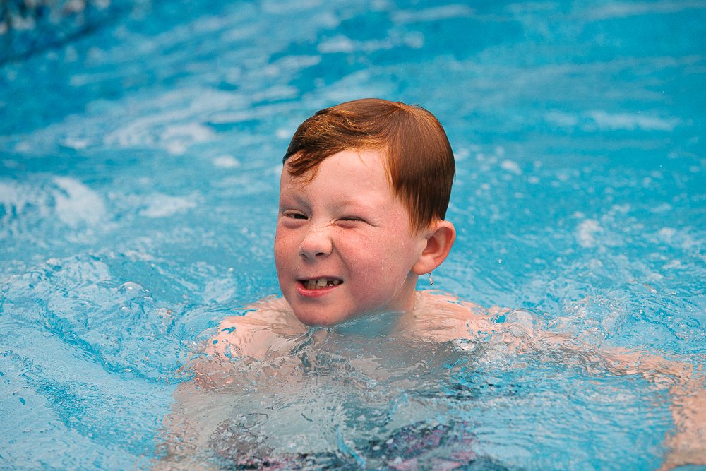 Little boy making weird faces in the pool looking at the camera