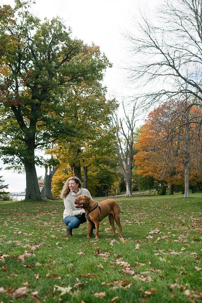 Mom playing with her brown mastiff dog in the park.