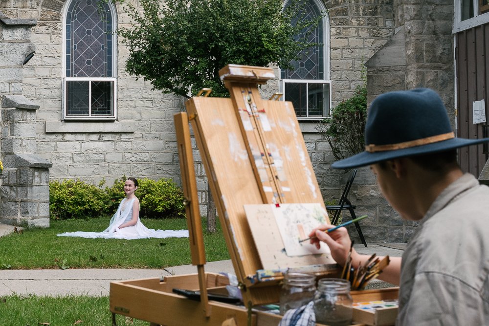 Artist painting the image of ballerina sitting in front of him