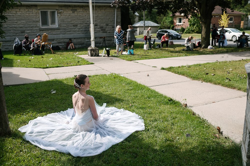 Ballerina posing for the artists sitting on the ground wearing white