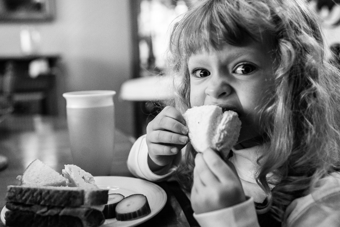 Black and white picture of a girl eating bread. 