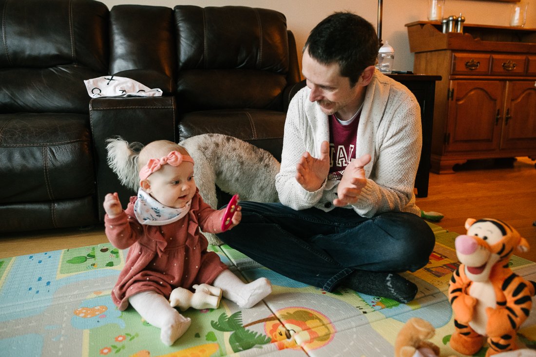 Father and daughter playing with toys sitting on mat
