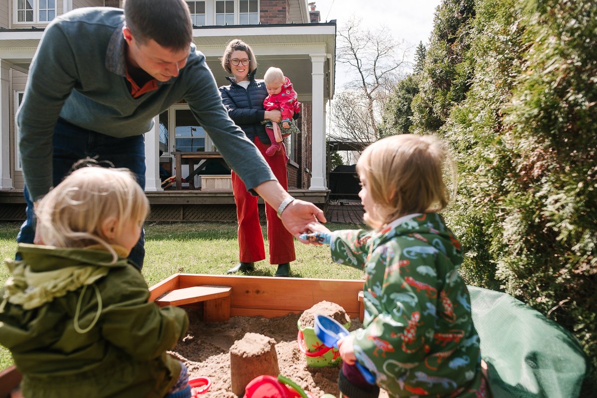 Girls playing in the sandbox on the backyard with their parents