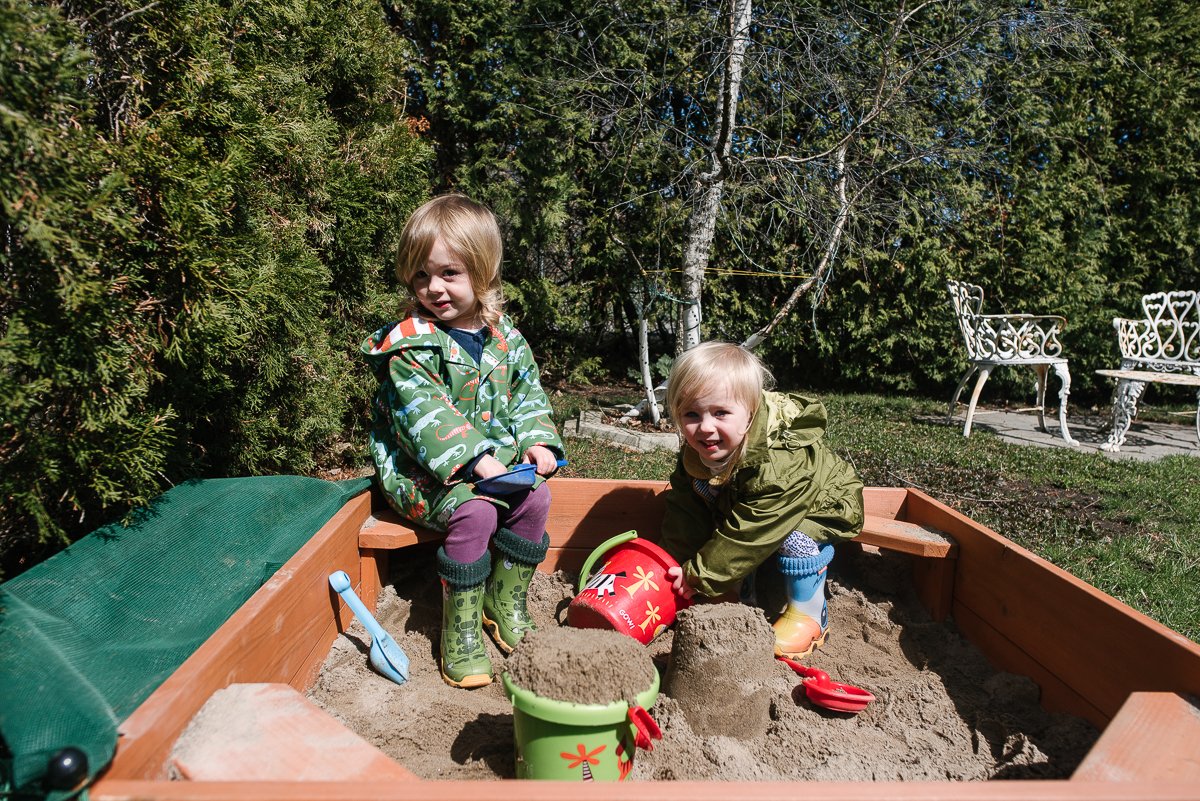 Kids playing in the sandbox in the backyard.