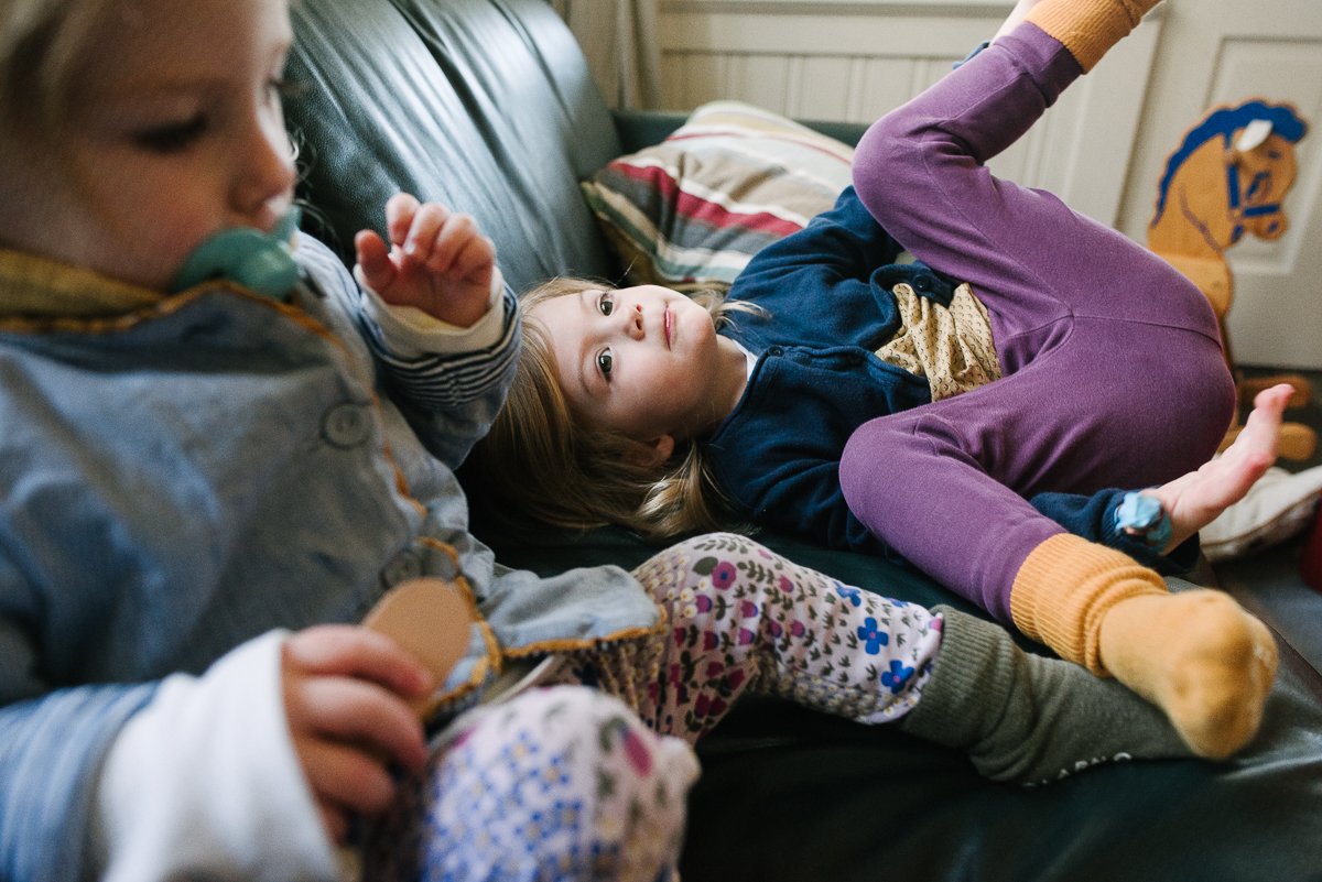 Girls playing on sofa in the living room lying down laughing