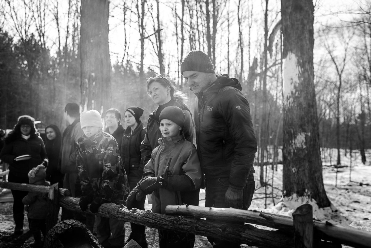 Black and white image of people seeing making of maple syrup