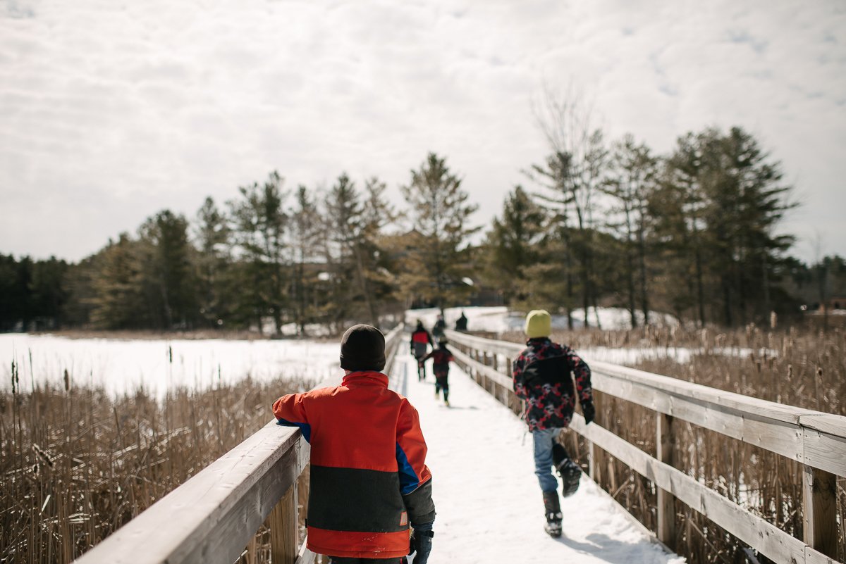 Parents and kids running in snow at Maple Madness at the Cataraqui Conservation Park. 