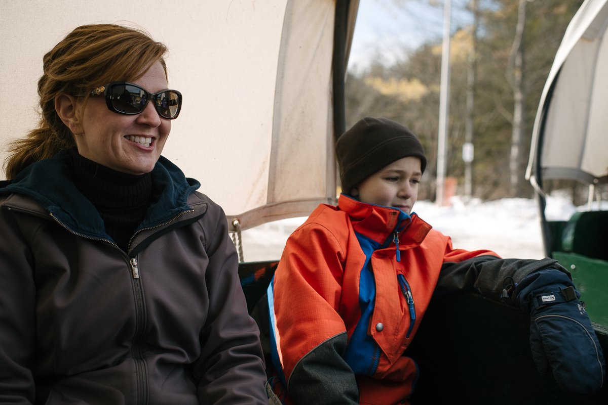 Mother and son sitting at the bench in Maple Madness at the Cataraqui Conservation Park. 