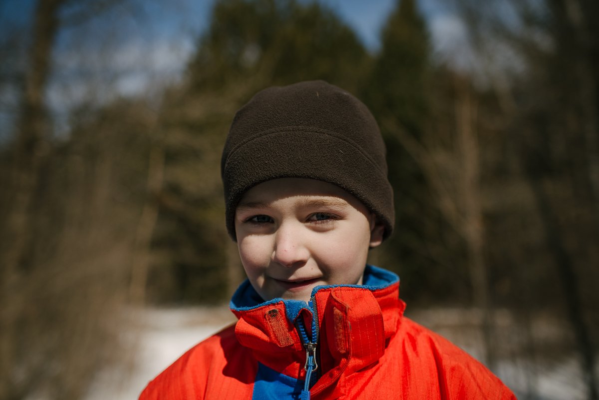 Close up of a boy wearing black winter cap and orange jacket