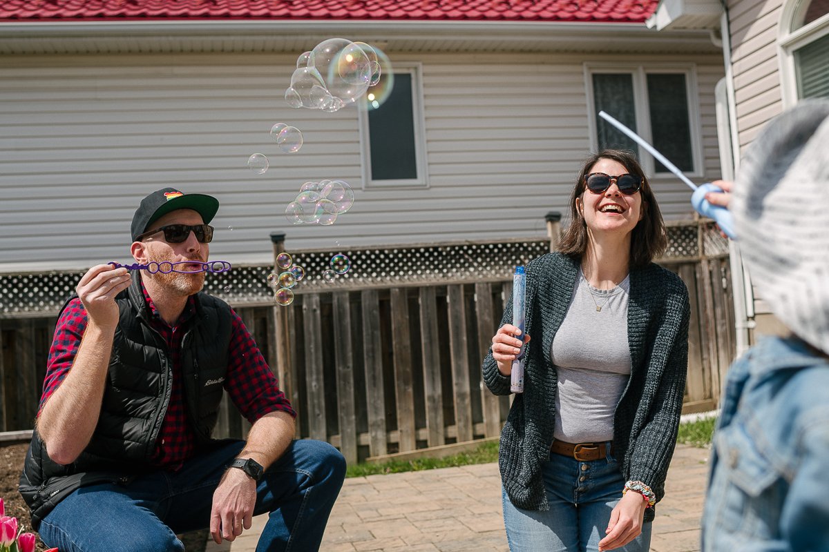 Mom dad and daughter blowing bubbles while playing in the playarea.