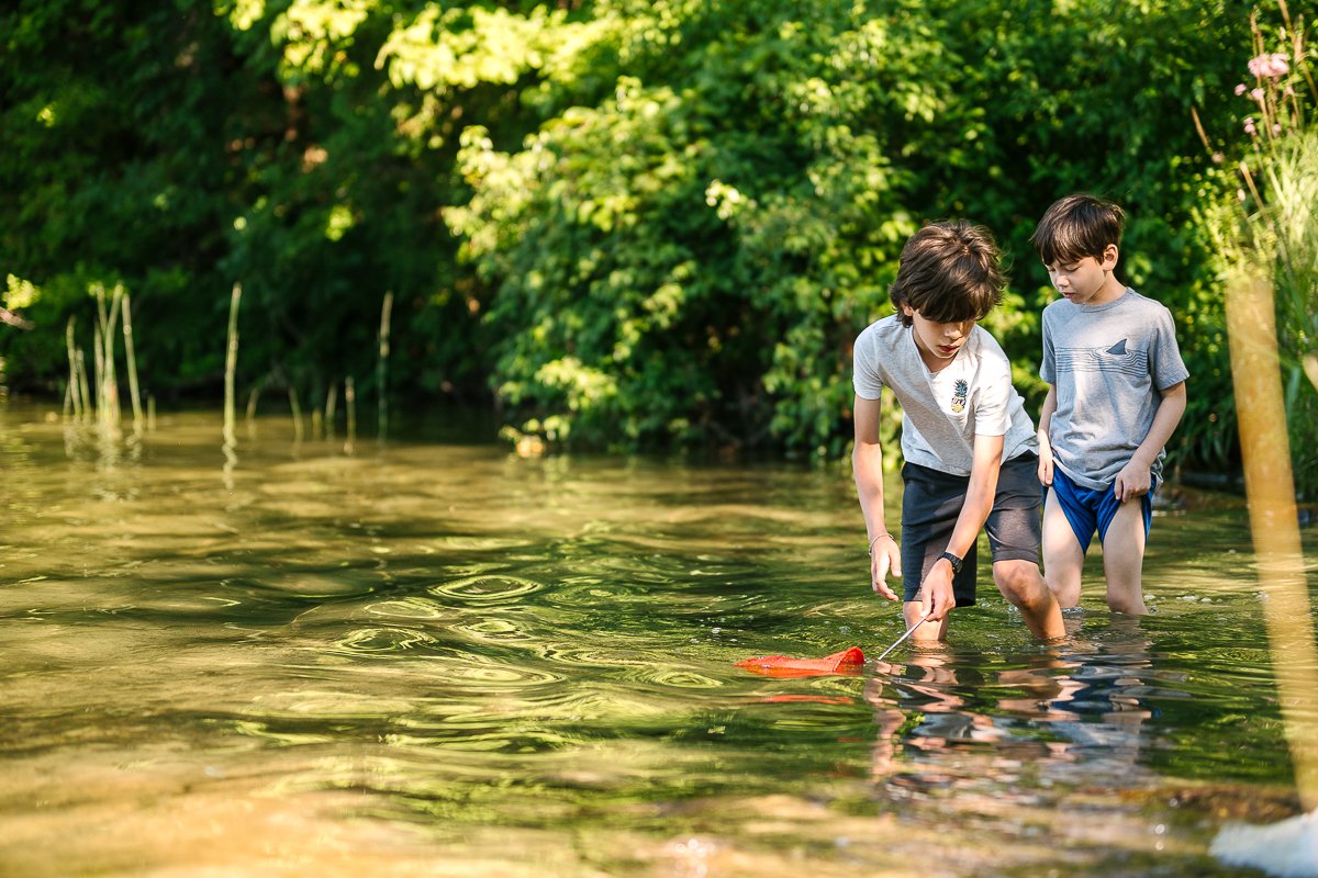 Boys playing in the water catching fish.