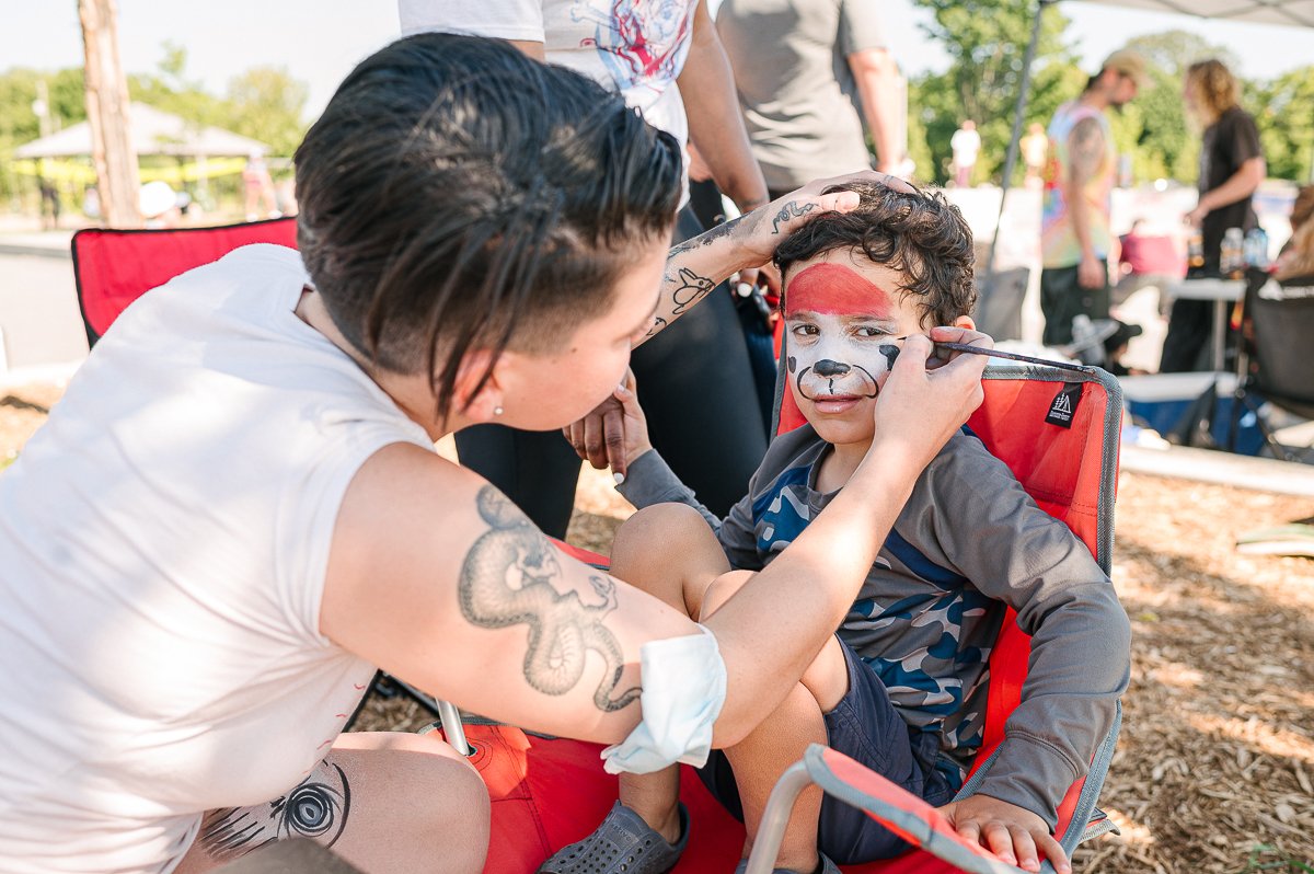 Woman doing face painting of a boy in the skating event.