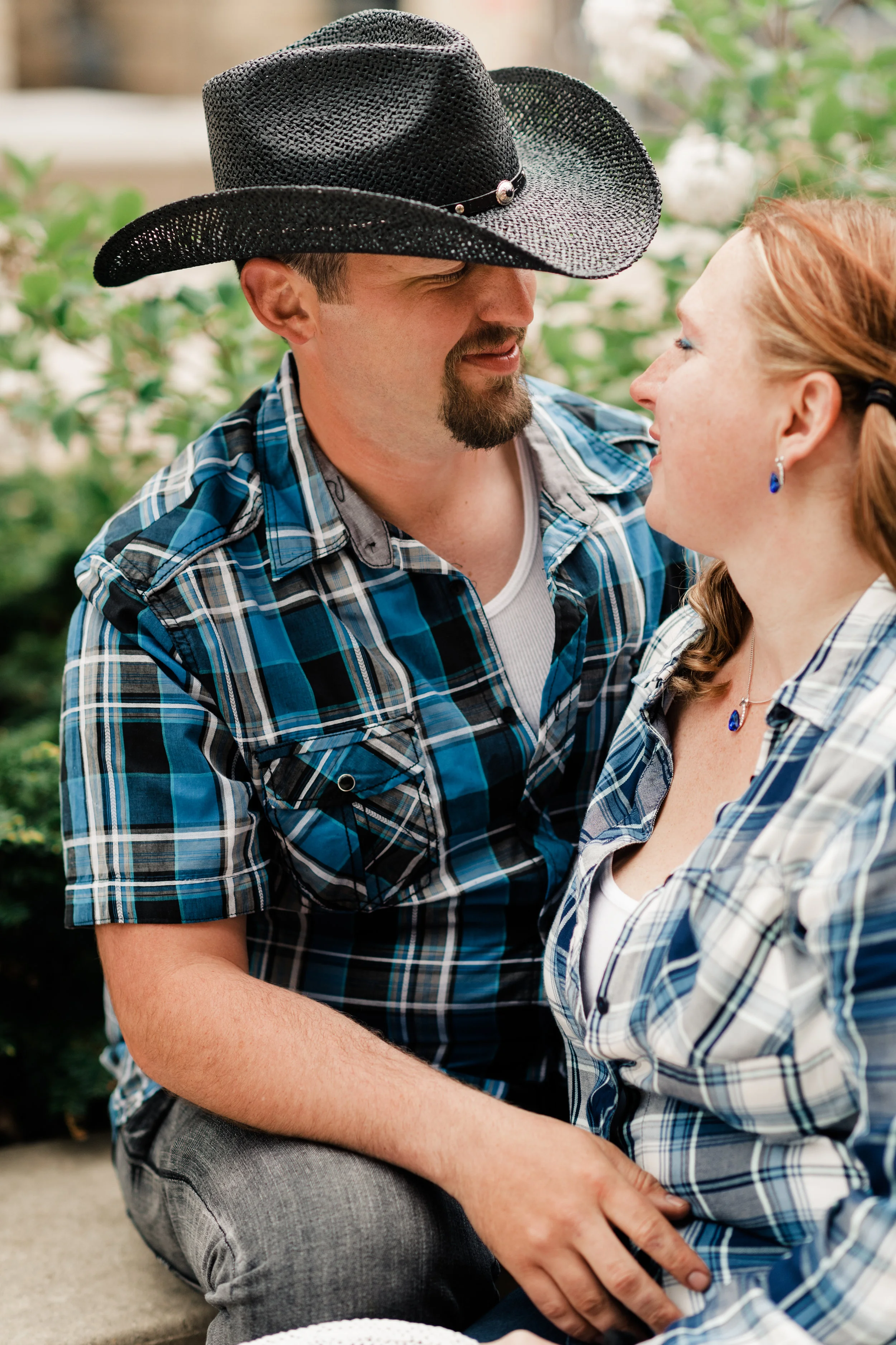 Engagement photo of couple looking at each other and wearing cowboy hats and plaid shirts at the Chazen Museum of Art in Madison, WI.