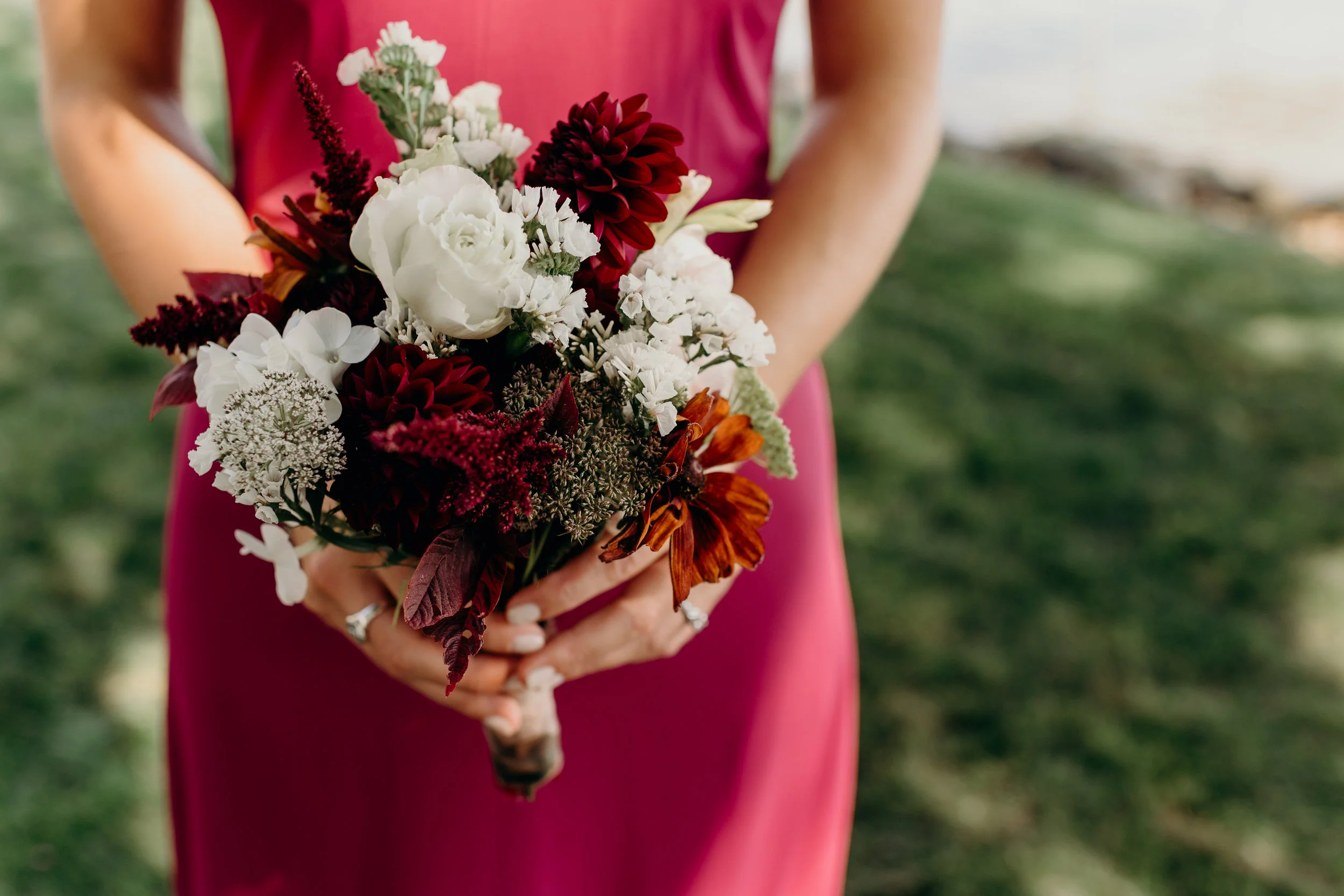 Bridesmaid's white and orange and burgundy bouquet.
