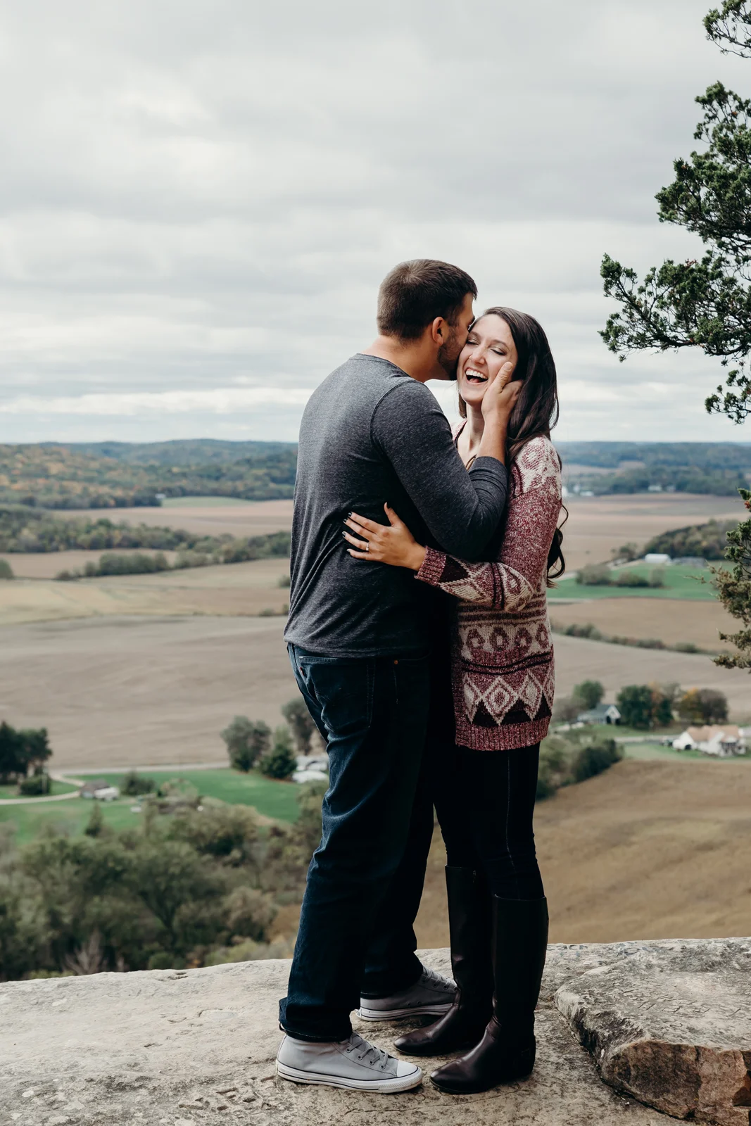 Woman laughs while her fiancé whispers in her ear.