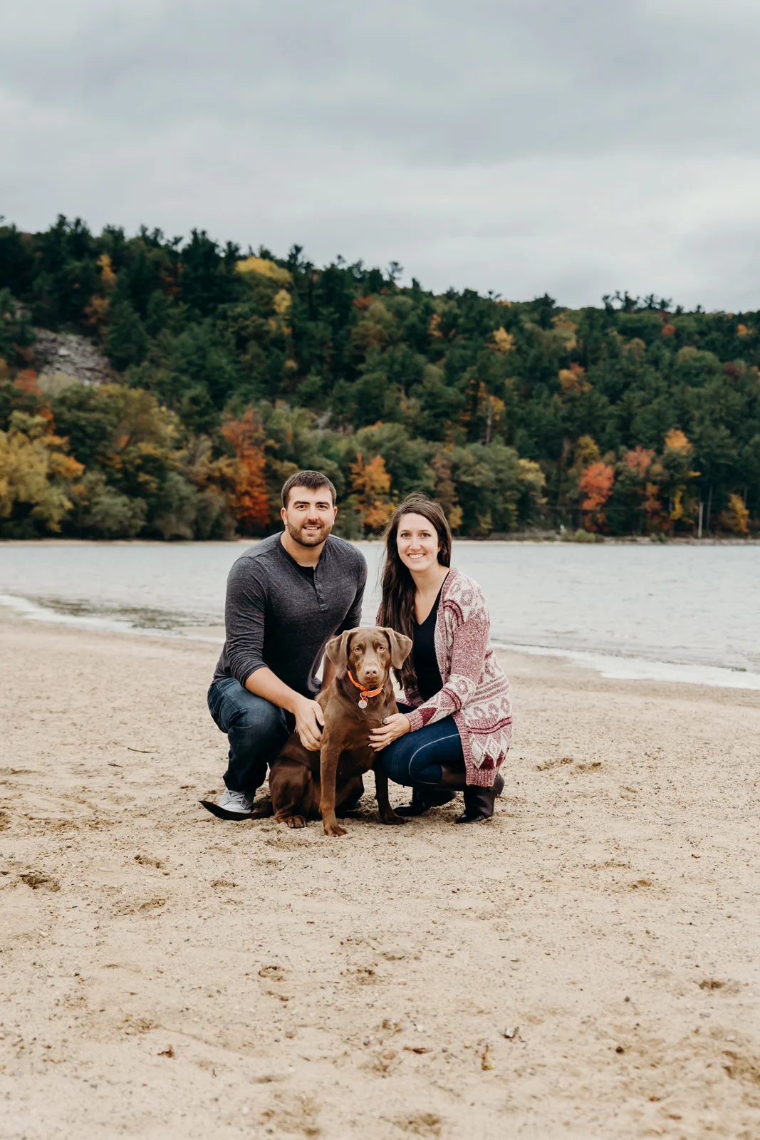 Engaged couple poses with their dog on the beach at Devil's Lake State Park in Baraboo, WI.