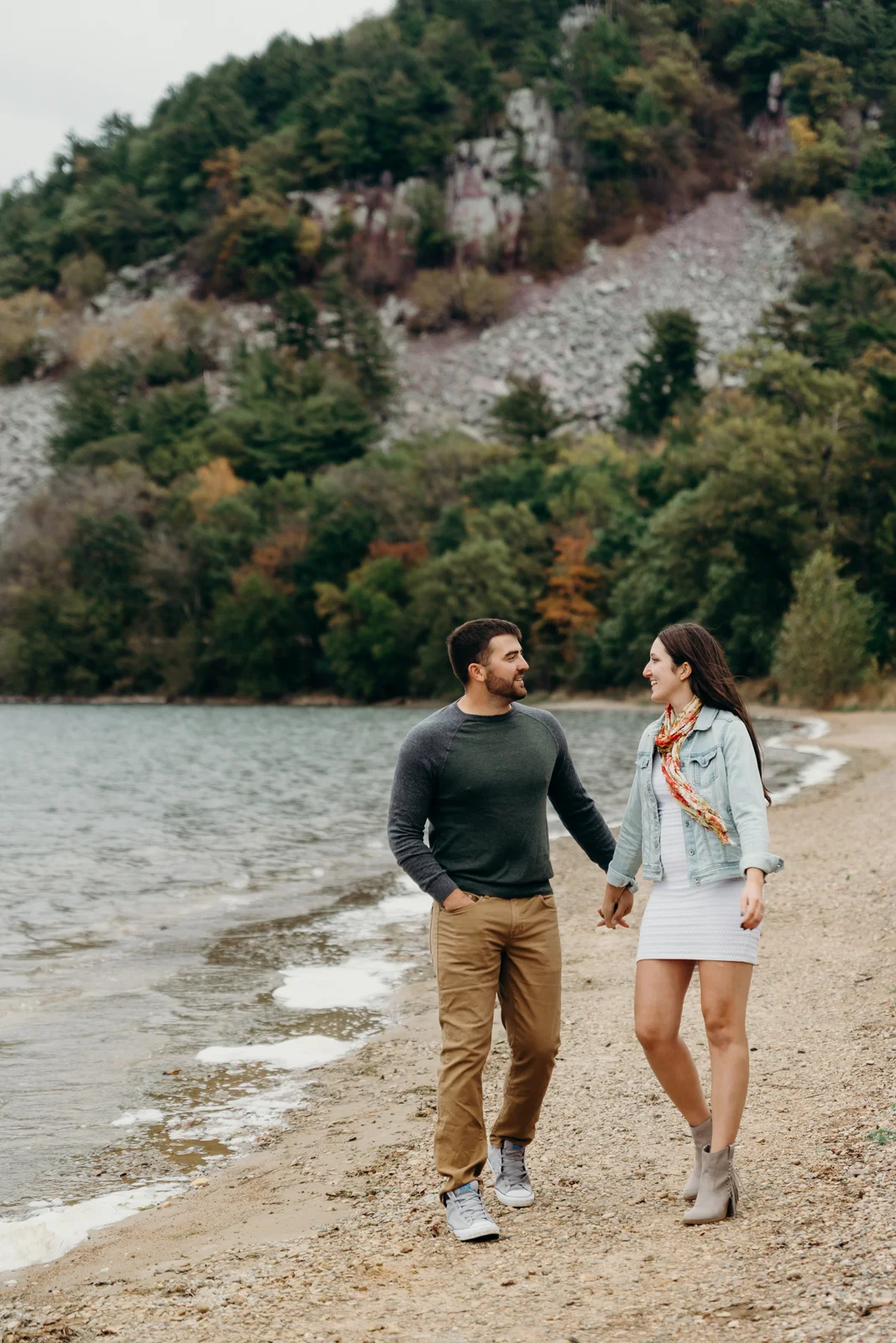 Engaged couple holds hands and looks at each other at Devil's Lake State Park.