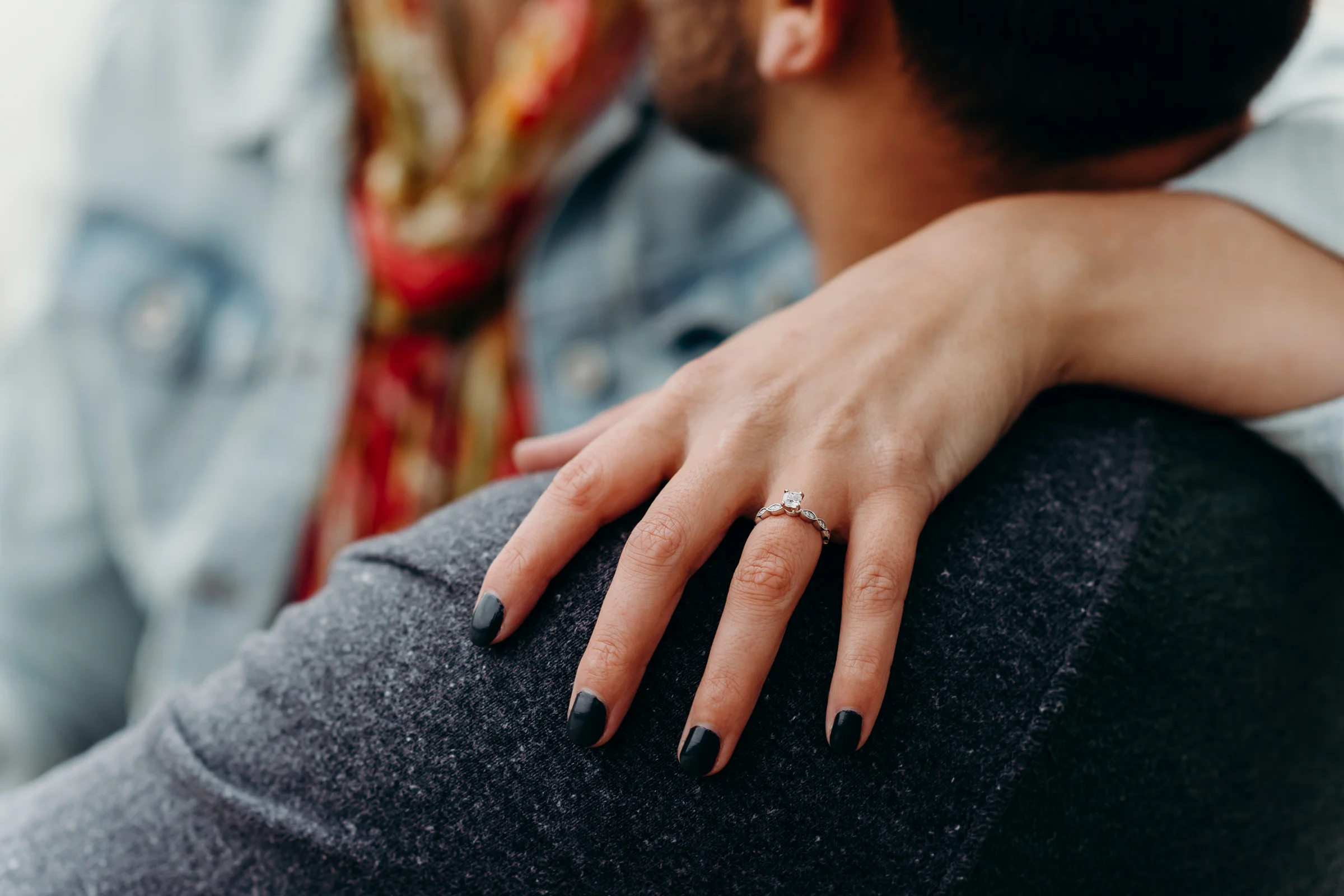 Woman wraps her arm around her fiancé showing off her princess cut engagement ring.