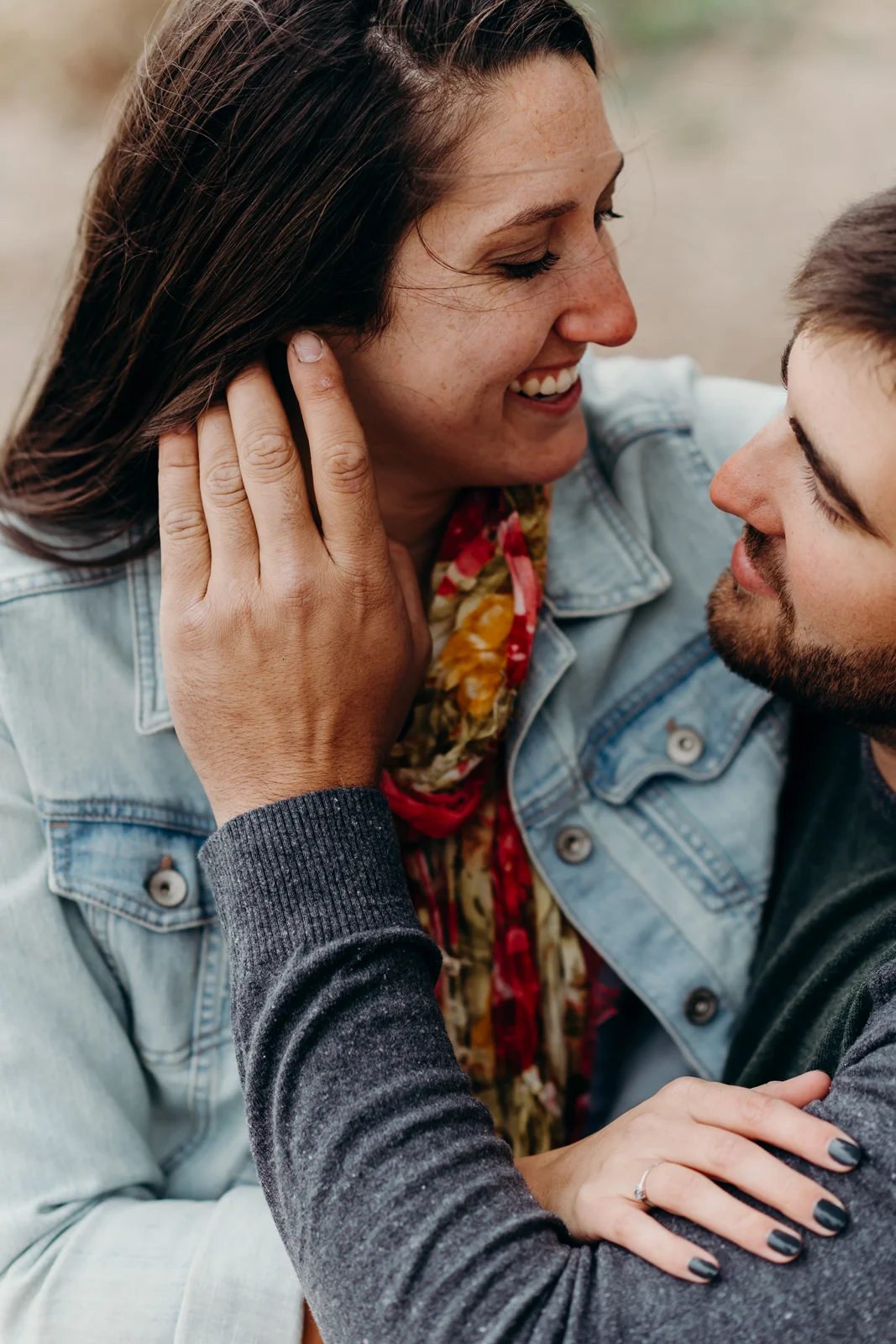 Woman smiles as her fiancé gently brushes his hand through her hair.