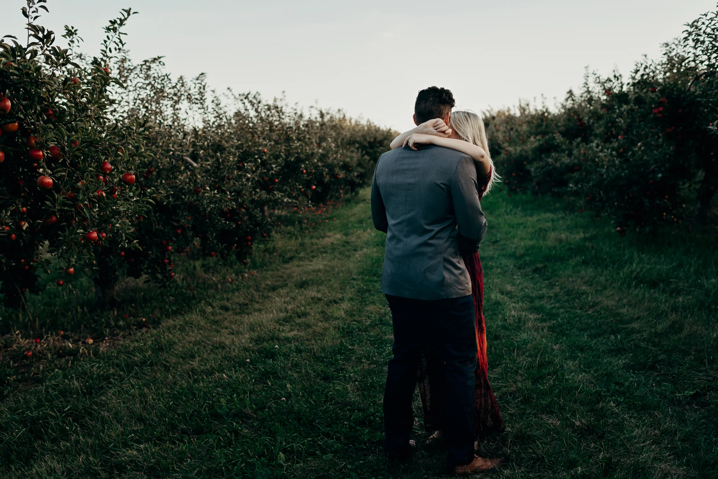 Engaged couple slow dances in an apple orchard.