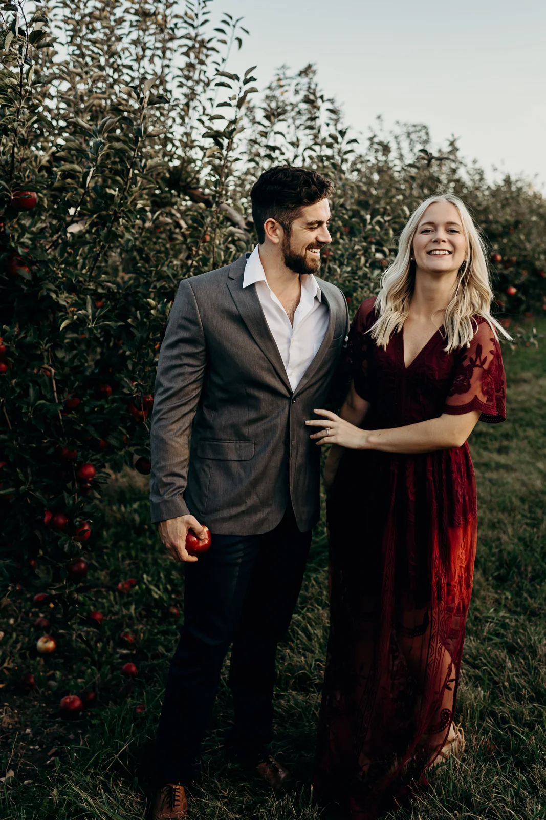Woman laughs as her fiancé holds an apple.