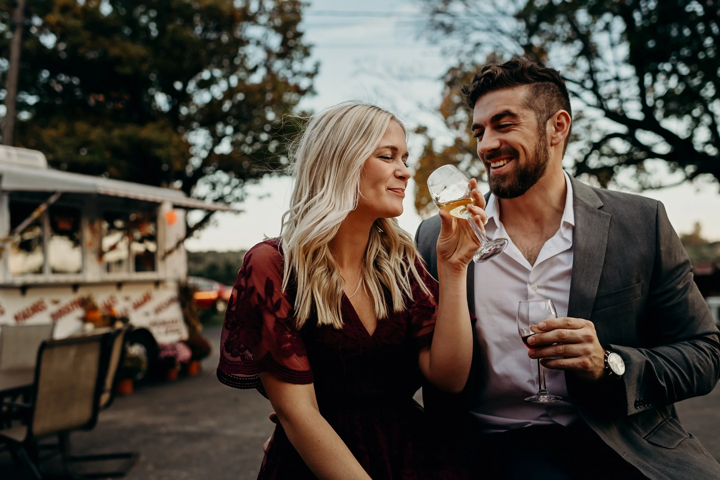 Engaged couple share a laugh and taste wine together.
