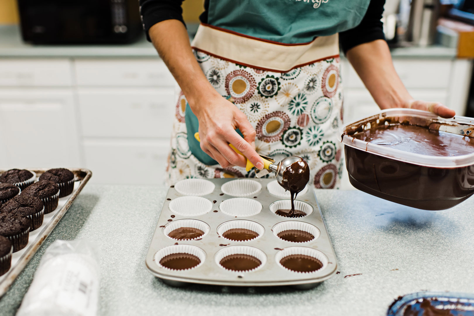 Scooping chocolate cupcake batter into muffin tin