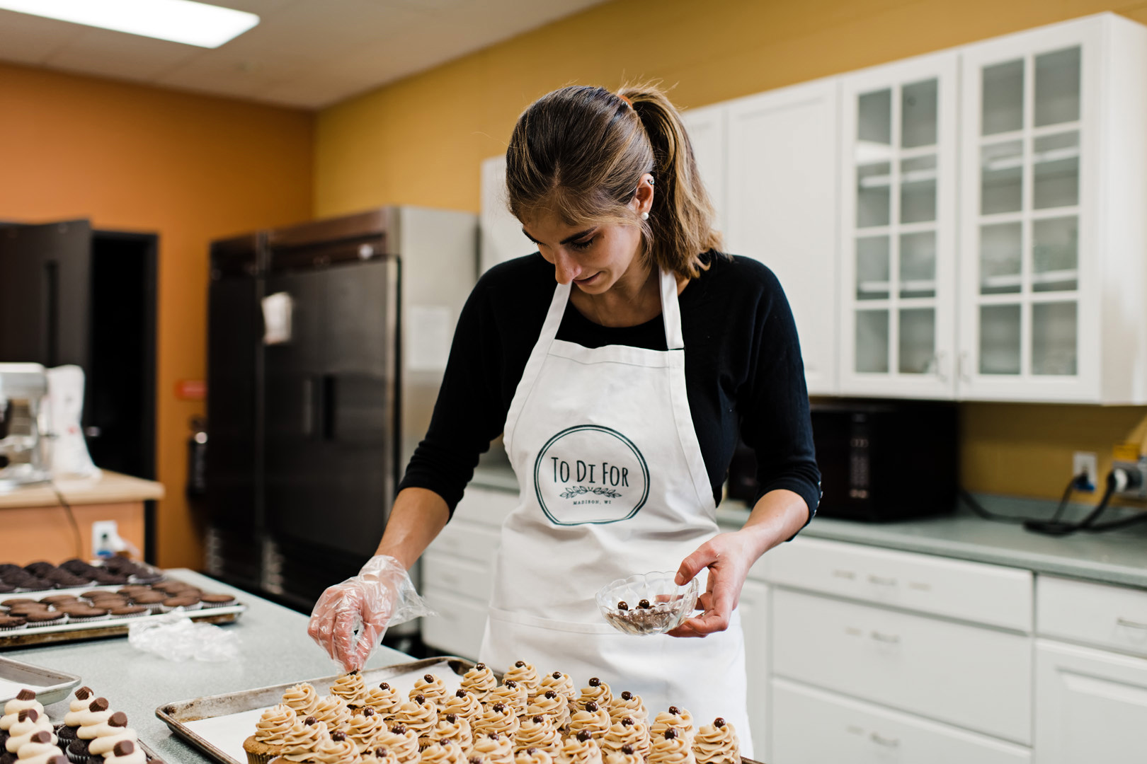 Owner of To Di For Baking topping cupcakes with chocolate covered coffee beans