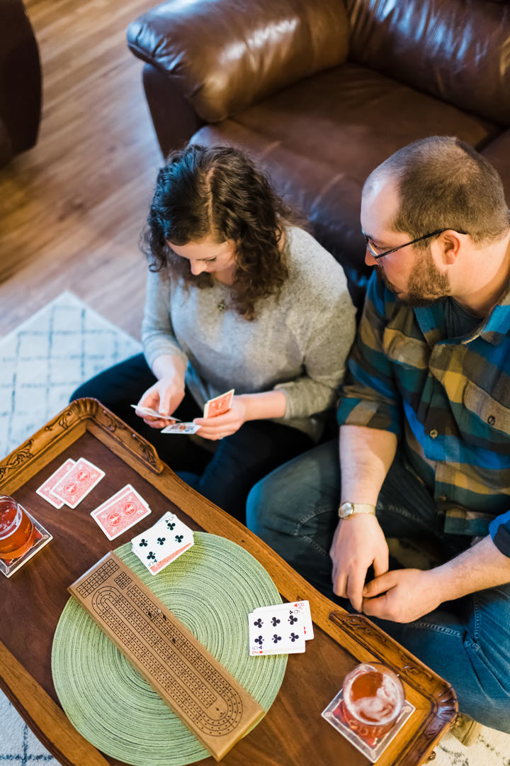 Man looks on as fiancé looks at her cribbage hand