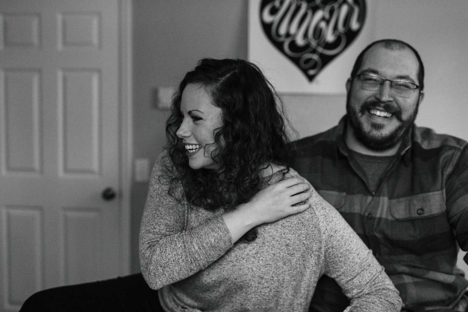 Engaged couple laughing on their bed