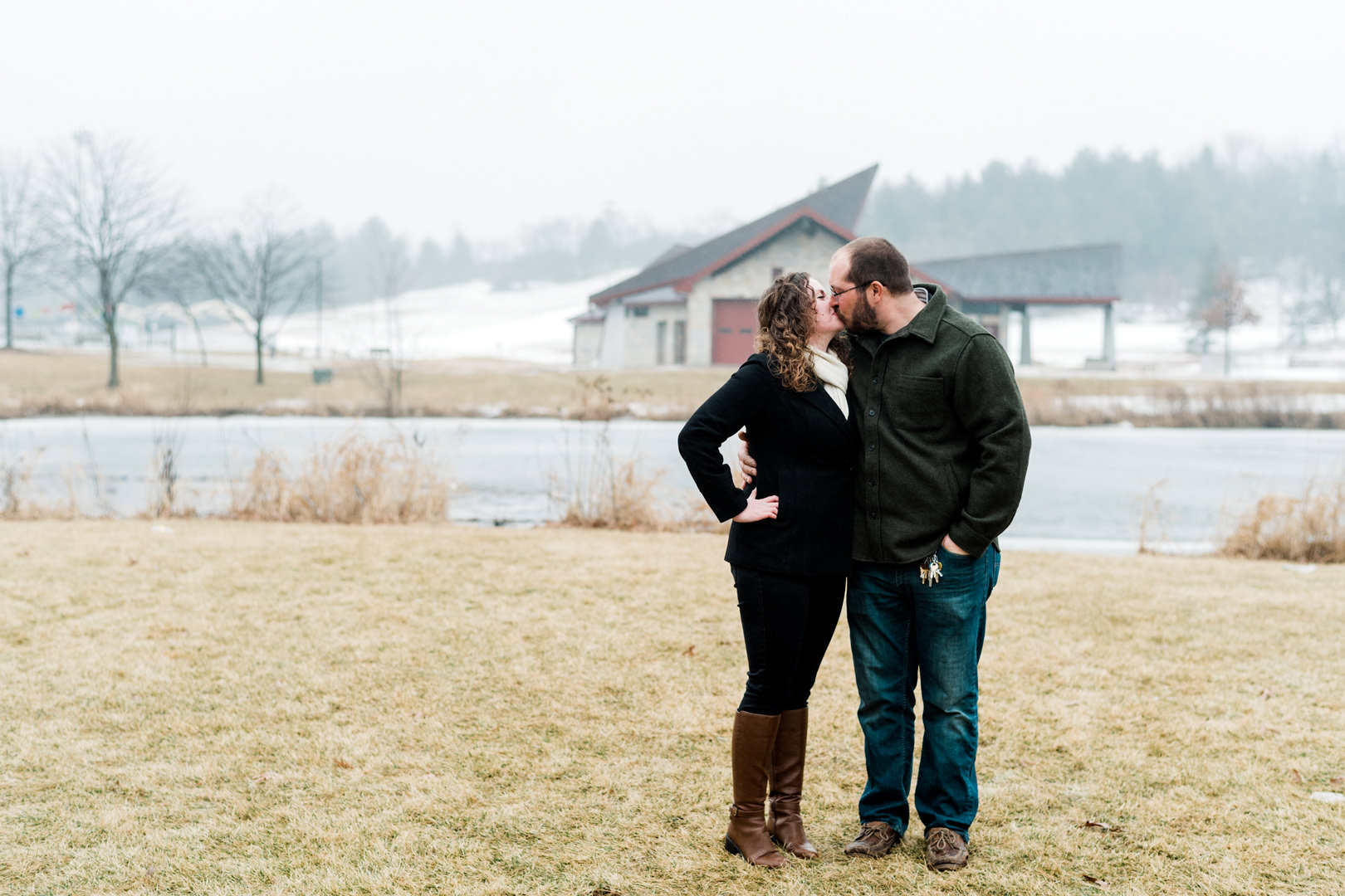 Engaged couple kissing outside on a misty day