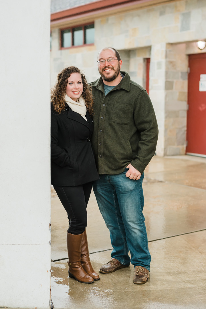 Engaged couple pose for a portrait against a pillar