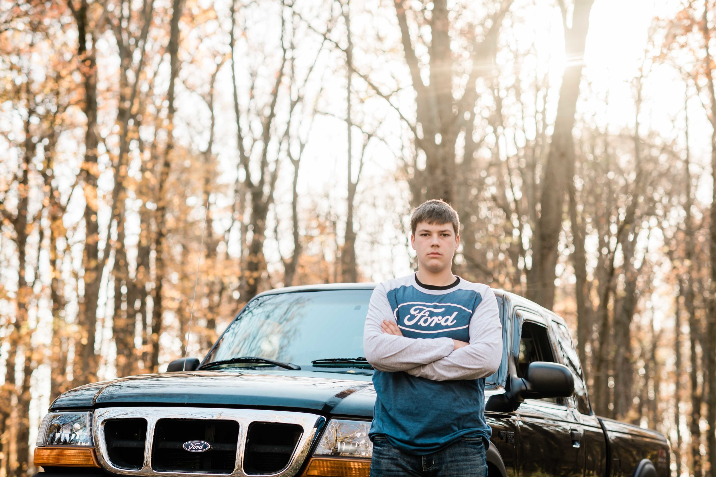 High school senior leans up against his truck