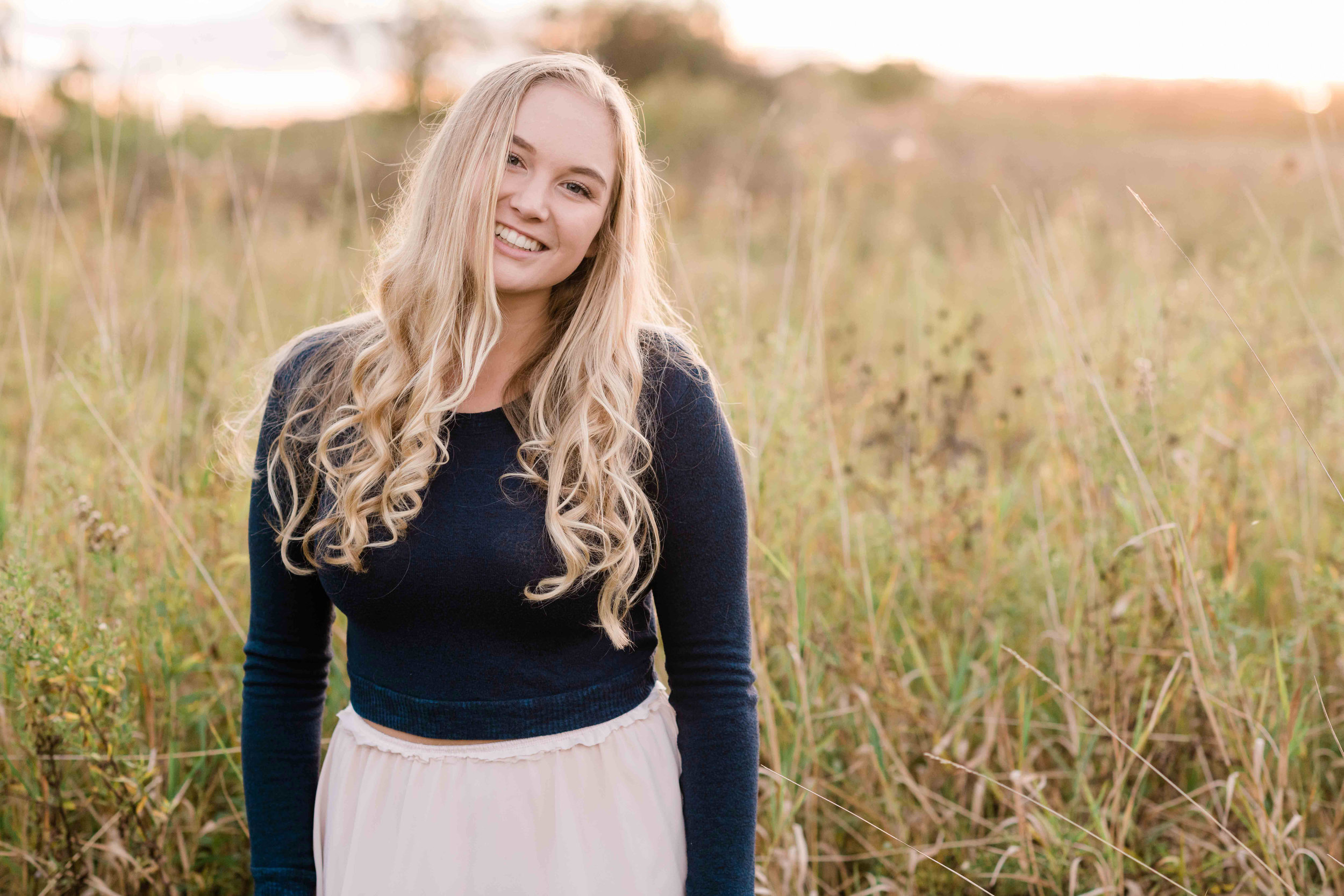 High school senior smiles in a field