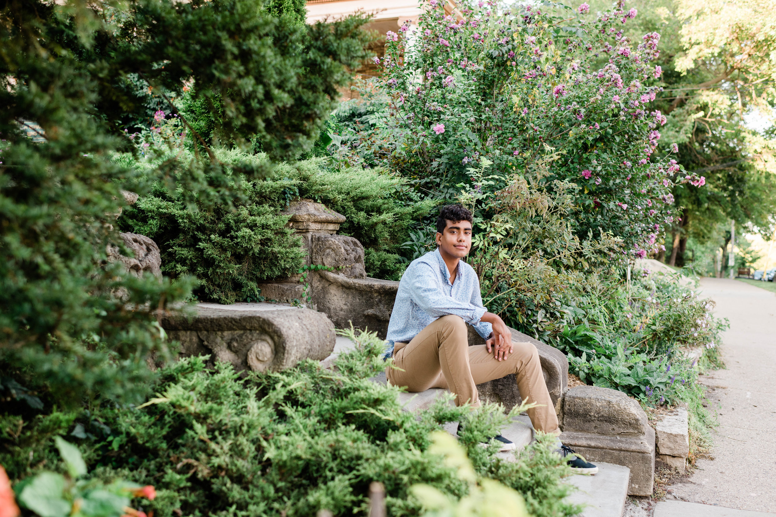 High school senior sitting on the steps at Period Garden Park