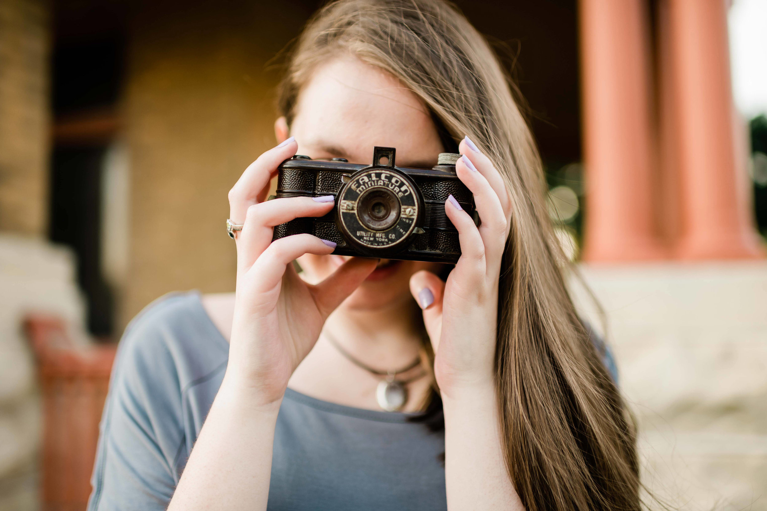 High school senior holding a camera up to her face